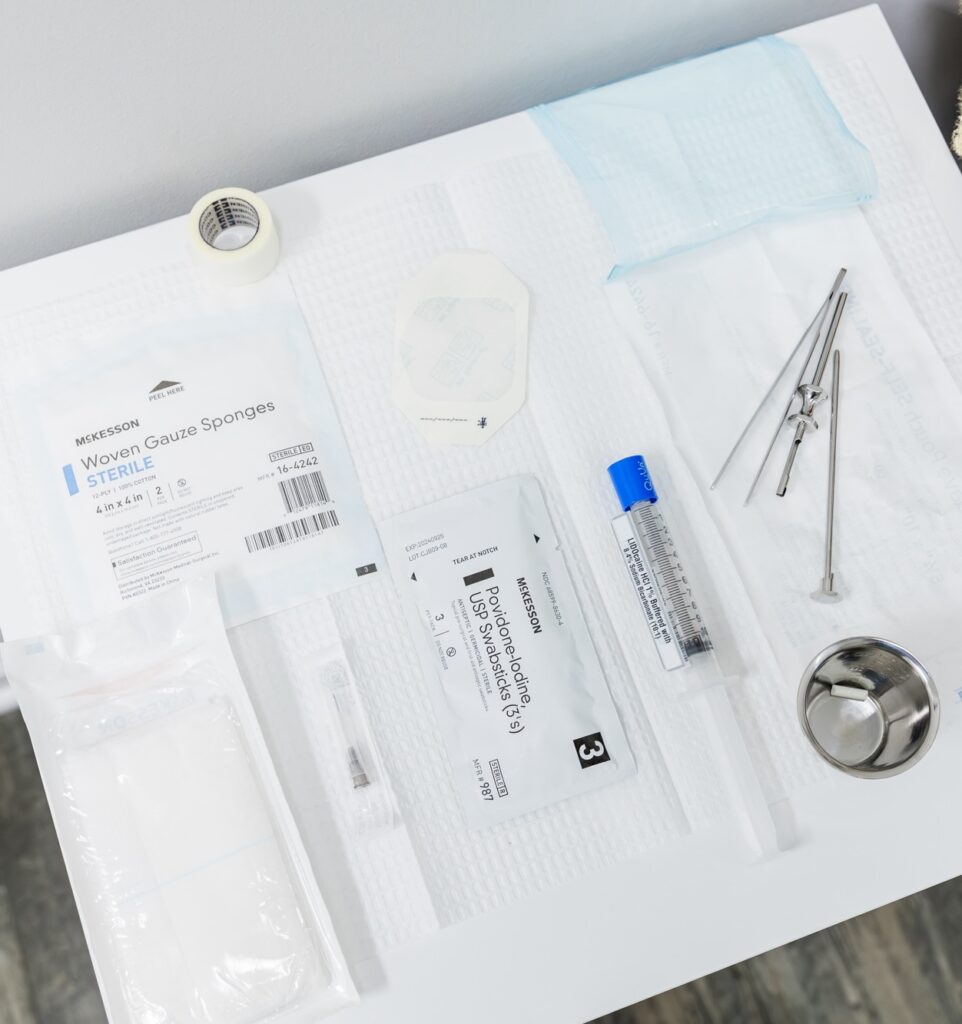 Various medical tools sit atop a sterile medical pad: gauzes, a bandage, tweezers, a small metal dish, and a insertion tool. These tools are used to insert the Biote pellet under the skin during a hormone replacement therapy near McGovern, PA.