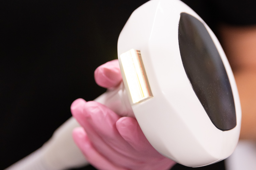 The handheld device used for intense pulsed light in Wheeling, WV. The provider's hand is visible, holding the device while wearing surgical gloves.